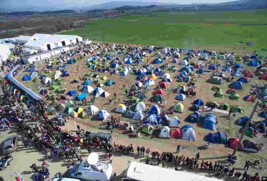 Para pengungsi dan migran antri untuk menerima pembagian makanan di kamp pengungsi Idomeni yang terletak di Yunani dekat perbatasan Makedonia.