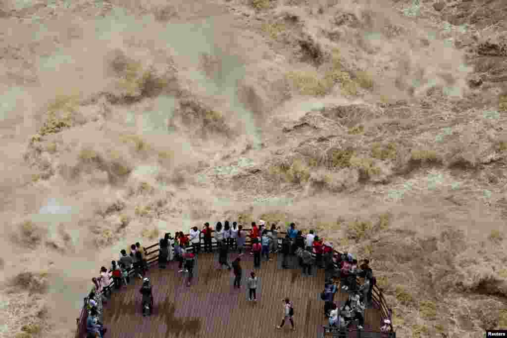 People watch the flooded Jinsha River at a sightseeing platform of Tiger Leaping Gorge, in Diqing, Yunnan Province, China.