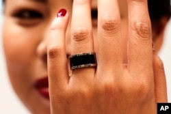 FILE - A woman shows a prototype of the Mota Smart Ring at the consumer electronic fair IFA in Berlin, Germany, Sept. 5, 2014. The smart ring is designed to notify users about incoming messages and phone calls, something, experts say, can be used to cheat on exams.