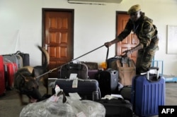 Kenya Wildlife Service (KWS) canine handler Patrick Musau leads his dog Rocco to sniff through luggages on February 12, 2016 at the Jommo Kenyatta International airport, Nairobi.