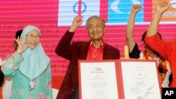 Malaysia former Prime Minister Mahathir Mohamad, center, and Wan Azizah, wife of former Deputy Prime Minister Anwar Ibrahim, wave during a political opposition alliance meeting in Shah Alam, Malaysia, Jan. 7, 2018.