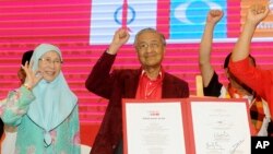 Malaysia former Prime Minister Mahathir Mohamad, center, and Wan Azizah, wife of former Deputy Prime Minister Anwar Ibrahim, wave during a political opposition alliance meeting in Shah Alam, Malaysia, Jan. 7, 2018.