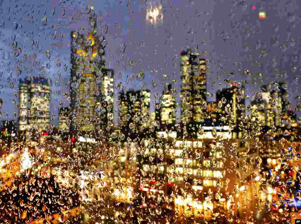 The buildings of the banking district are seen through thousands of rain drops on a glass railing in central Frankfurt, Germany.