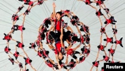 Students of Shaolin Tagou Martial Arts School are suspended in mid-air as they rehearse for the 2014 Youth Olympic Games' opening ceremony in Naning, China, Aug. 9, 2014.