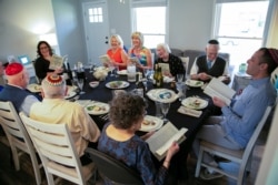 People laugh and joy as they read the Haggadah that haven't been able to do in person last year during a Passover Seder dinner party for 10 people vaccinated against the coronavirus disease, in Louisville, Kentucky, U.S. March 27, 2021. (REUTERS/Amira Karaoud)