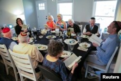 People laugh and joy as they read the Haggadah that haven't been able to do in person last year during a Passover Seder dinner party for 10 people vaccinated against the coronavirus disease, in Louisville, Kentucky, U.S. March 27, 2021. (REUTERS/Amira Karaoud)
