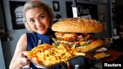 Seorang pelanggan menunjukan burger terbesar di Thailand seberat 6kg yang dibuat restoran Chris Steaks & Burgers sebelum kompetisi makan burger itu di Bangkok, Thailand, 11 Oktober 2019. (Foto: Reuters)