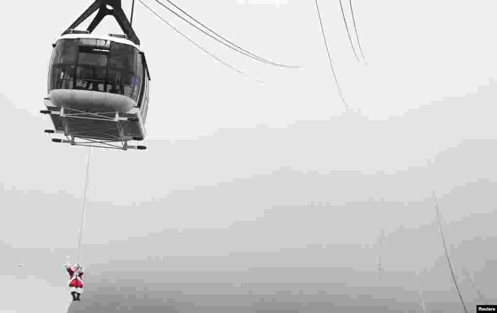 A man dressed as Santa Claus rappels from a cable car while descending from the Pao de Acucar Mountain (Sugar Loaf Mountain) during his arrival to a Christmas event in Rio de Janeiro, Brazil, Dec. 5, 2020.