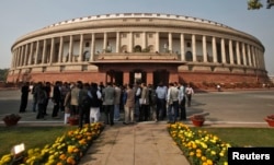 Orang-orang berdiri di depan gedung parlemen India di New Delhi, 22 November 2012. (Foto: Reuters)