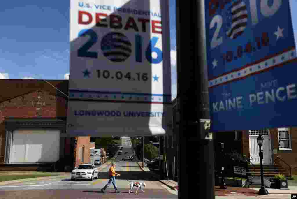 A pedestrian crosses a street as signs advertising the vice presidential debate hang along South Main Street in Farmville, Va.
