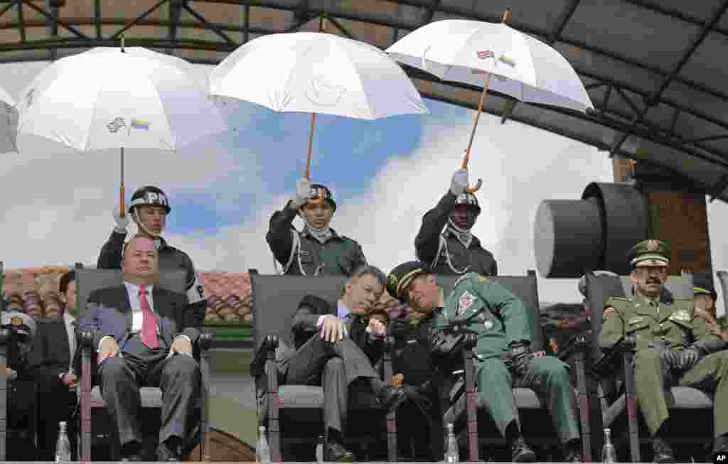 លោកប្រធានាធិបតីកូឡុំប៊ី Juan Manuel Santos (កណ្តាលមើលពីខាងឆ្វេង) អោនស្តាប់លោកនាយកឧត្តមសេនីយ៍កងកម្លាំងប្រដាប់អាវុធ Juan Pablo ក្នុងអំឡុងពេលពិធីយោធាមួយនៅក្នុងទីក្រុង Bogota ប្រទេសកូឡុំប៊ី ។