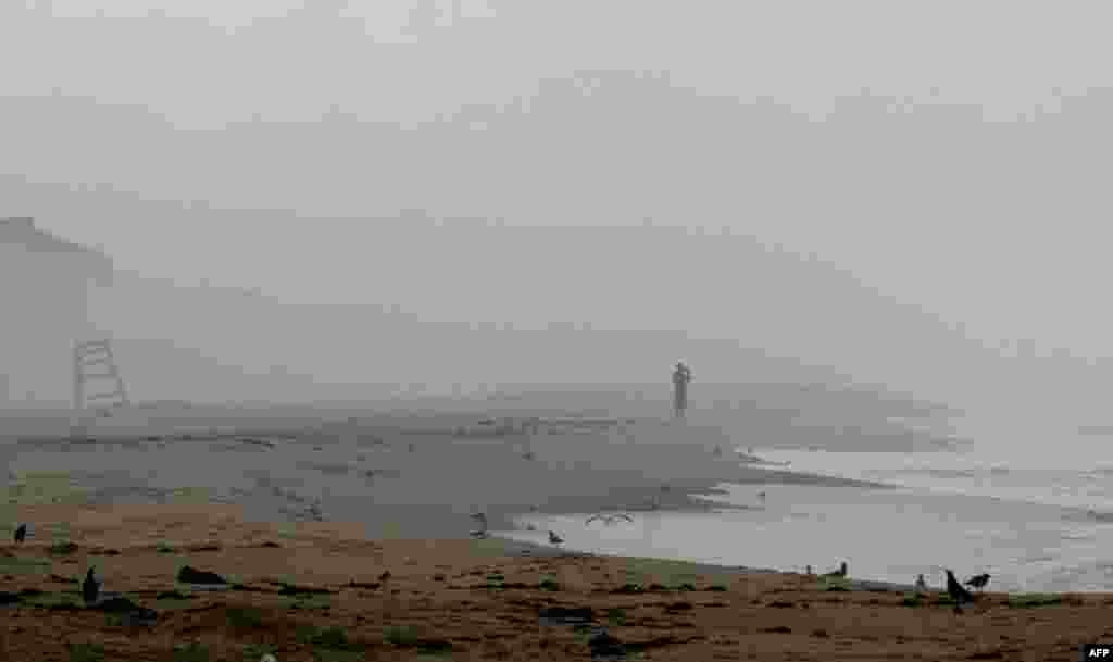 August 26: A beachgoer in Nags Head, N.C., remains despite evacuation orders for Hurricane Irene. Waves began hitting North Carolina's Outer Banks early Friday. (AP Photo/Gerry Broome)