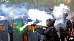 Seorang polisi menembakkan gas air mata saat bentrok dengan para mahasiswa yang berunjuk rasa di Surabaya, Jawa Timur, 8 Oktober 2020. (Foto: AP)