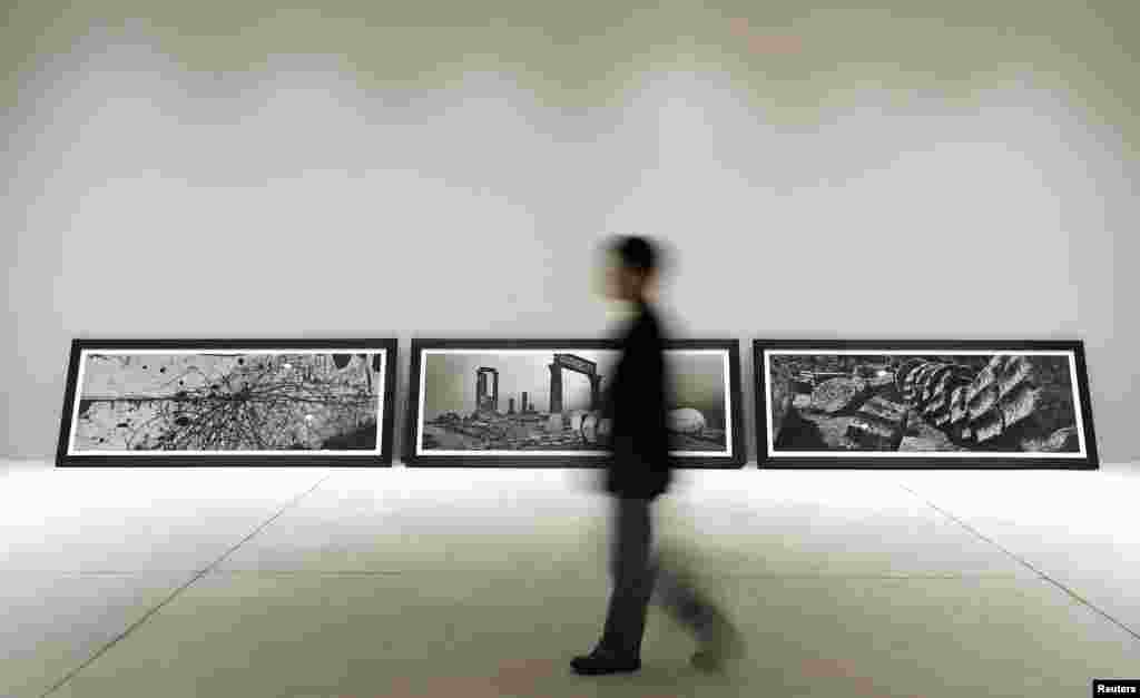 A visitor walks past pictures representing the &quot;uncreation&quot; theme, by famed Czech photographer Josef Koudelka, at the Holy See pavilion, May 28, 2013. The Holy See has its own pavilion this year for the first time. 