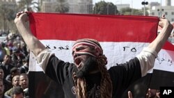 An Egyptian protester holds a national flag and chants anti-ruling military council slogans during a protest after Friday prayers at Tahrir Square, in Cairo, February 10, 2012.