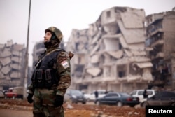 A member of forces loyal to Syria's President Bashar al-Assad stands near damaged buildings in Aleppo's Salaheddine district, Syria, Dec. 16, 2016.