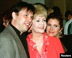FILE - Carrie Fisher, her mother, actress Debbie Reynolds, and brother, filmmaker Todd Fisher, arrive at a luncheon hosted by the American Film Institute, Sept. 17, 1998.