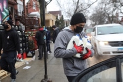 Miguel Angel Leonardo membawa susu ke kendaraan saat makanan didistribusikan di Chicago, Illinois, AS, 16 Maret 2021. (Foto: REUTERS/Daniel Acker)