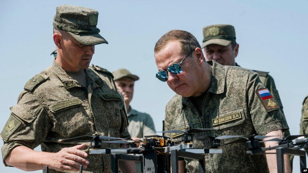 ARCHIVO - El vicepresidente del Consejo de Seguridad de Rusia y jefe del partido Rusia Unida, Dmitri Medvédev, a la derecha, escucha a un oficial mientras visita el campo de entrenamiento militar de Pogonovo, en la región rusa de Vorónezh, el 17 de julio de 2024.