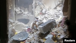 A Civil Defense member looks for survivors at a site hit by what activists said were two barrel bombs dropped by forces loyal to Syria's President Bashar al-Assad in the Al-Shaar neighborhood of Aleppo, July 27, 2014. 