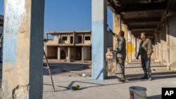 FILE - People repaint a part of their home that was damaged during the war during the Assad regime, in Saraqib, on the outskirts of Idlib, Syria, Jan. 15, 2025. 