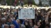 Demonstrators hold a placard reading "Don't sign it, Janos" referring to President Janos Ader as they protest against the amendment of the higher education law seen by many as an action aiming at the closure of the Central European University, founded by Hungarian born American billionaire businessman George Soros, in front of the Parliament building in Budapest, Hungary, Apr. 9, 2017. 