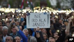 Demonstrators hold a placard reading "Don't sign it, Janos" referring to President Janos Ader as they protest against the amendment of the higher education law seen by many as an action aiming at the closure of the Central European University, founded by Hungarian born American billionaire businessman George Soros, in front of the Parliament building in Budapest, Hungary, Apr. 9, 2017. 