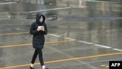 A woman crosses a deserted street in Melbourne's central business district on August 19, 2020, as the city battles an outbreak of the COVID-19 coronavirus. - Australia should make any coronavirus vaccine compulsory for its 25 million citizens bar…