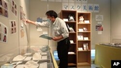 In this photo provided by curator Makoto Mochida of the Historical Museum of Urahoro, Mochida examines the newspaper clips and other items he is collecting to document how life was affected by the coronavirus pandemic at the museum in Urahoro, Hokkaido, n