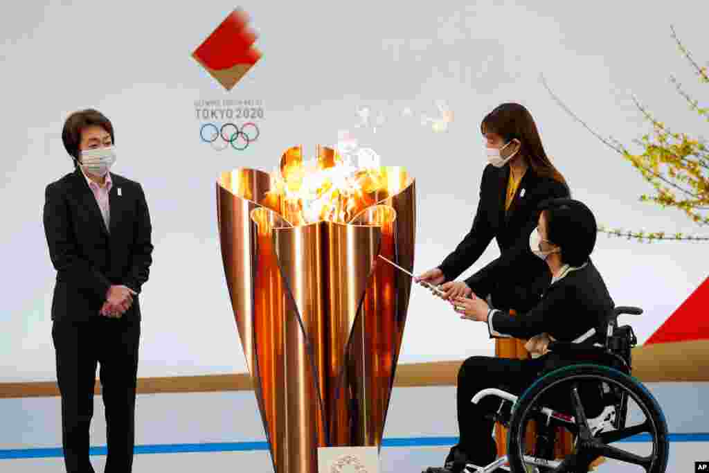 Tokyo 2020 President Seiko Hashimoto, left, watches Japanese actress Satomi Ishihara and Paralympian Aki Taguchi light the celebration cauldron on the first day of the Tokyo 2020 Olympic torch relay in Naraha, Fukushima prefecture, Japan.