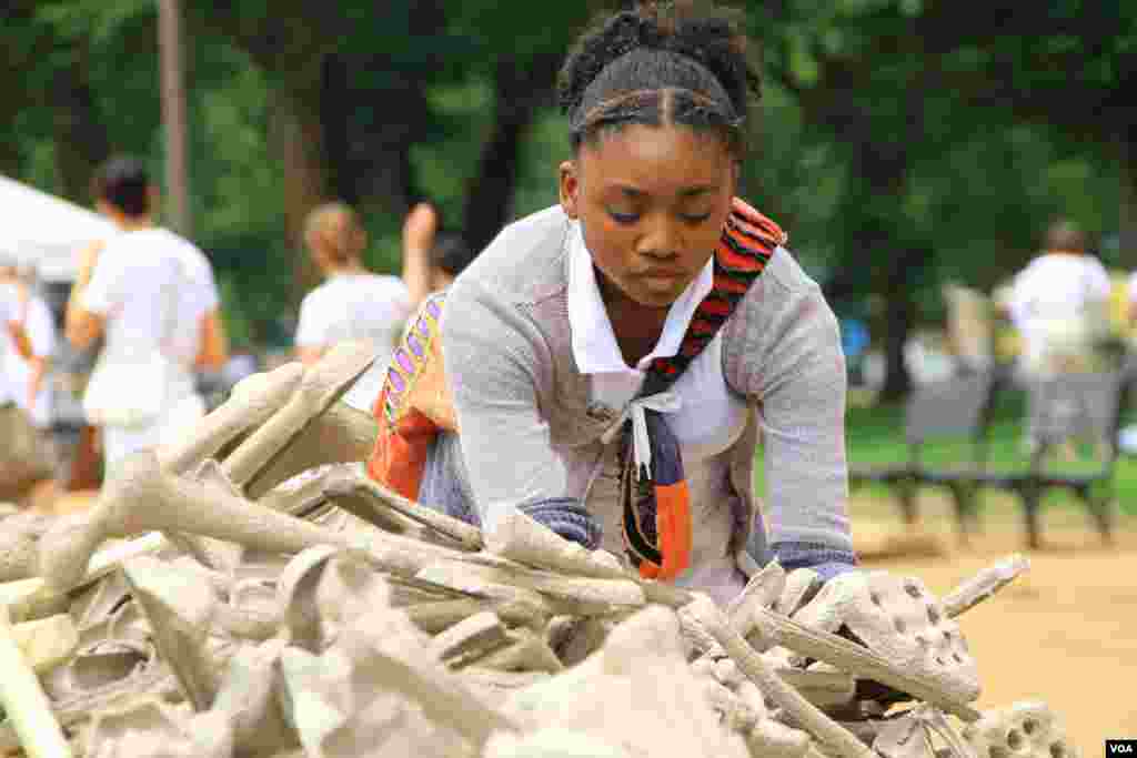 A girl selects artificial bones for display at the &quot;One Million Bones&quot; installation on the National Mall, Washington, D.C, June 8, 2013. (Jill Craig/VOA)