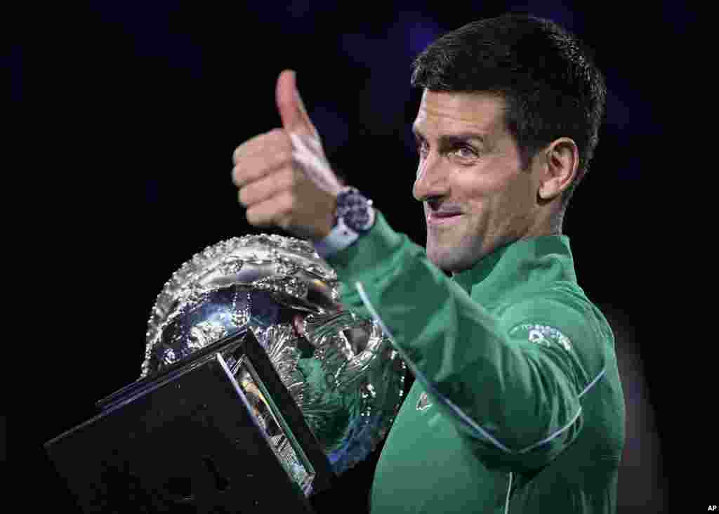 Serbia&#39;s Novak Djokovic gestures as he holds the Norman Brookes Challenge Cup after defeating Austria&#39;s Dominic Thiem in the final of the Australian Open tennis championship in Melbourne, Australia.