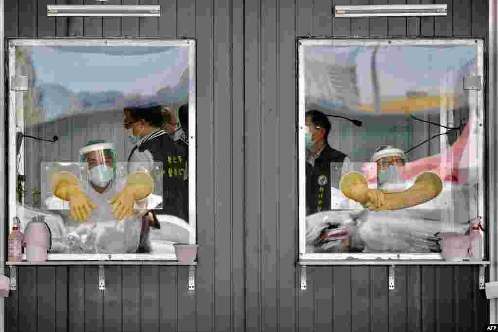 Medical personnel are seen behind their sealed work areas at a swab test screening area for COVID-19 in New Taipei City, Taiwan.