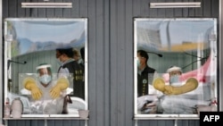 FILE - On June 8, 2021, medical personnel are seen behind their sealed work areas at a swab test screening area for COVID-19 in New Taipei City, Taiwan.