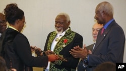 Le sculpteur sénégalais Ousmane Sow, au centre, reçoit son épée académique de Marieme Faye, épouse du président sénégalais Macky Sall, ex-président sénégalais Abdou Diouf, applaudit lors d'une cérémonie à l'Académie française de Paris, le mercredi 11 décembre 2013. 