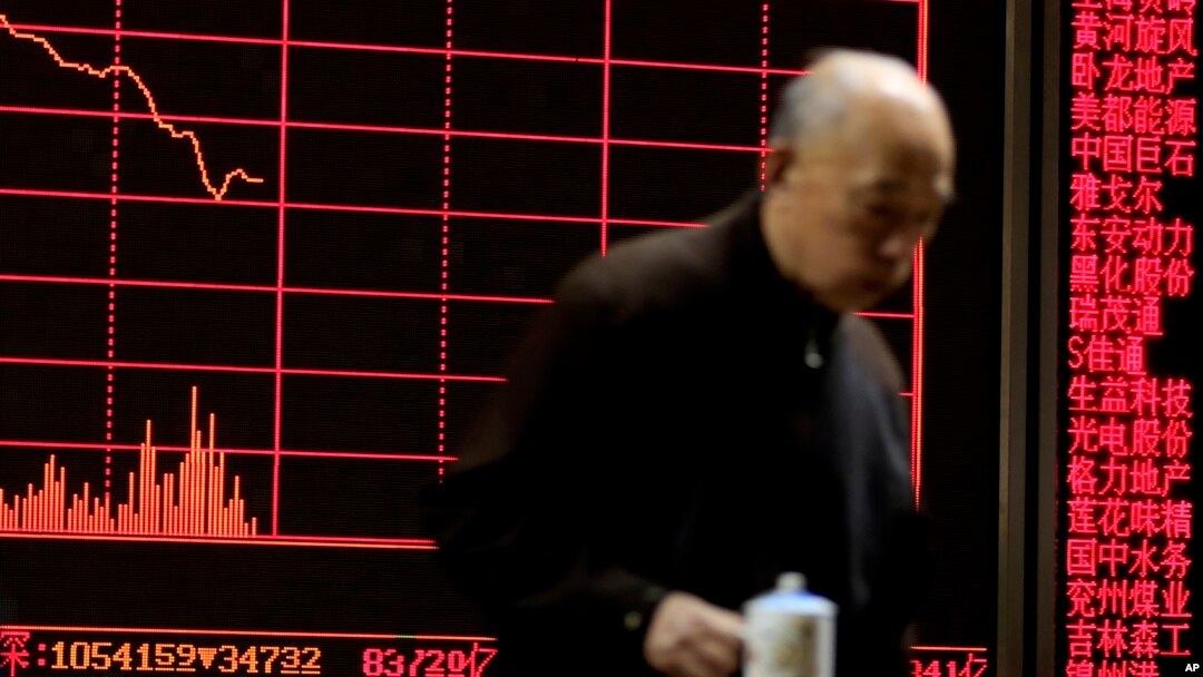 A man walks past an electronic board displaying stock prices at a brokerage house in Beijing, Monday, Jan. 11, 2016.