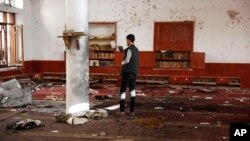 FILE - A man uses his mobile phone to take pictures inside a Shiite mosque hit by two bombs in Sana'a, Yemen, Sept. 3, 2015. 