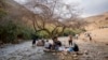 FILE - Palestinians sit under a tree in a spring near al-Auja village of the Jordan Valley, in the West Bank, Feb. 25, 2023.