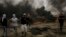 Palestinian protesters run for cover from tear gas fired by Israeli troops after they burn tires during a protest at the Gaza Strip's border with Israel, east of Khan Younis, May 4, 2018. 