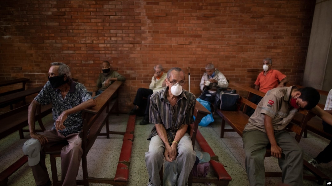 Personas, usando tapabocas como medida de precaución contra la propagación del coronavirus, esperan recibir una comida gratis en una iglesia en el barrio El Cementerio de Caracas, Venezuela. Mayo 22, 2020.