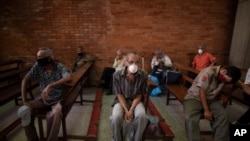 Personas, usando tapabocas como medida de precaución contra la propagación del coronavirus, esperan recibir una comida gratis en una iglesia en el barrio El Cementerio de Caracas, Venezuela. Mayo 22, 2020.