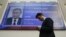 A man walks past a screen showing preliminary results of Russian President Vladimir Putin in the presidential election, at the headquarters of Russia's Central Election Commission in Moscow, March 19, 2018. 