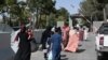 Afghans, hoping to leave Afghanistan, walk through the main entrance gate of Kabul airport in Kabul on Aug. 28, 2021.