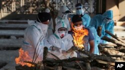 Para kerabat dari seorang pasien COVID-19 yang meninggal menyalakan api di tempat pembakaran jenazah di sebuah krematorium di Jammu, India, Senin, 26 April 2021. (Foto: Channi Anand/AP)