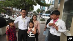 Journalists Uon Chhin, right, and Yeang Sothearin with his children enter the municipal court in Phnom Penh, Cambodia, Aug. 9, 2019. The two Cambodian journalists were on trial on espionage charges rights groups call a flagrant attack on press freedom.