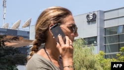 FILE - An woman talks on her iPhone while passing in front of the building housing the Israeli NSO Group, in Herzliya, near Tel Aviv, Aug. 28, 2016.
