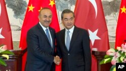 Menteri Luar Negeri Turki Mevlut Cavusoglu (kiri) berjabat tangan dengan Menlu China Wang Yi usai konferensi pers bersama di Beijing, Kamis (3/8). 