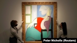 Karyawan berpose untuk berfoto dengan "Femme Assise Pres d'Une Fenetre (Marie-Therese)”, karya Pablo Picasso di galeri Christie sebelum penjualan malam musim semi New York, di London, Inggris, 22 April 2021. (Foto: REUTERS/Peter Nicholls)