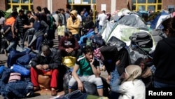 Refugees and migrants sit next to their belongings before boarding a bus heading to other parts of the country where they will be accommodated, at the port of Piraeus, near Athens, Greece, March 31, 2016.