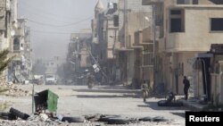 Syrian army soldiers stand along a street in Palmyra, a city in Homs, April 1, 2016 after retaking the city from Islamic State militants. 